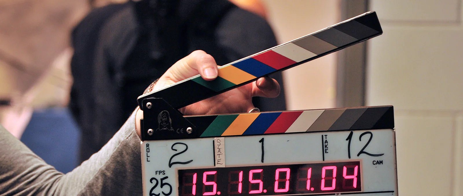 Dłoń trzymająca klaps filmowy z numerami roll, scene i take